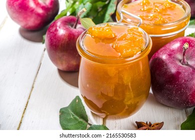 Homemade golden colored apple jam, with farm red apples and leaves on white wooden background copy space - Shutterstock ID 2165530583