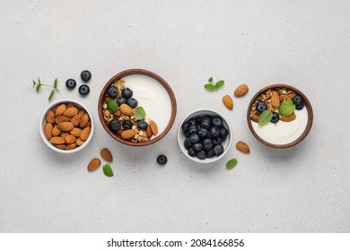 Homemade granola with berries and yoghurt. Bowl of Greek yogurt with almond nuts, oat granola and fresh blueberries on white background - Powered by Shutterstock