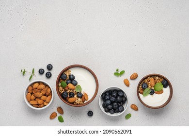 Homemade Granola With Berries And Yoghurt. Bowl Of Greek Yogurt With Almond Nuts, Oat Granola And Fresh Blueberries On White Background