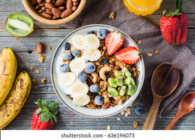 Homemade granola with nuts and raisins, kiwi, blueberries, banana, strawberries and plain yogurt. Top view. Concept of healthy lifestyle, dieting, healthy eating and breakfast