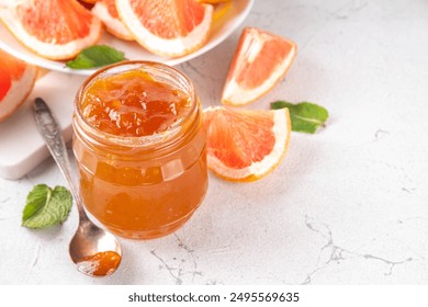 Homemade grapefruit jam, sweet pink grapefruit marmalade in small jar, with grapefruit slices and mint leaves on white table background - Powered by Shutterstock