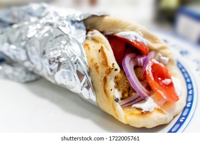 Homemade Greek Pita Chicken Souvlaki Kalamaki Wrap Opened With Tzatziki Yogurt Sauce, Chicken Skewers, Red Onion And Tomato.
Traditional Greek Street Food.
Wrapped In Aluminum Foil Ready To Take Away.