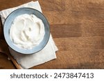 Homemade Greek Yogurt in blue bowl on wooden background, top view, copy space. Organic plain greek yogurt, labneh cream cheese, sour cream for healthy breakfast.