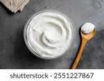 Homemade Greek Yogurt or Labne in bowl on grey stone background, top view. Organic plain greek yogurt with spoon, labneh cream cheese, whipped cream.