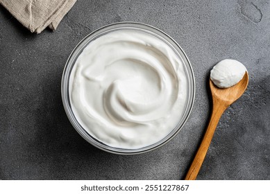 Homemade Greek Yogurt or Labne in bowl on grey stone background, top view. Organic plain greek yogurt with spoon, labneh cream cheese, whipped cream.