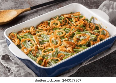 Homemade Green Bean Casserole with crispy fried onions on the baking dish on the table. Horizontal
