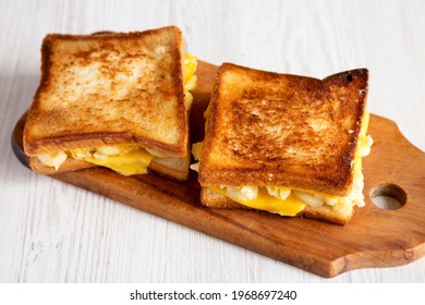 Homemade Grilled Macaroni and Cheese Sandwich on a rustic wooden board on a white wooden table, side view. 