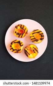 Homemade Grilled Peaches On A Pink Plate On A Black Background, Top View. Flat Lay, Overhead, From Above. Close-up.