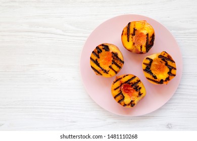 Homemade Grilled Peaches On A Pink Plate On A White Wooden Background, Top View. Flat Lay, Overhead, From Above. Copy Space.