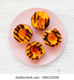 Homemade Grilled Peaches On A Pink Plate On A White Wooden Surface, Top View. Flat Lay, Overhead, From Above. Close-up.