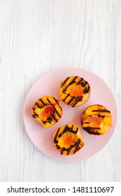 Homemade Grilled Peaches On A Pink Plate On A White Wooden Background, Top View. Flat Lay, Overhead, From Above. Copy Space.