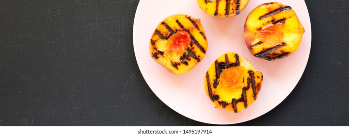 Homemade Grilled Peaches On A Pink Plate On A Black Background, Top View. Flat Lay, Overhead, From Above. Copy Space.