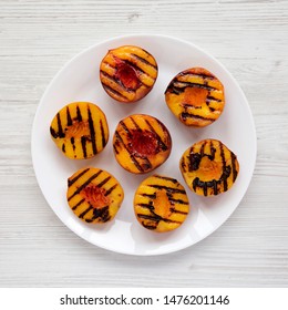 Homemade Grilled Peaches On A White Plate On A White Wooden Table, View From Above. Flat Lay, Top View, Overhead. Close-up.