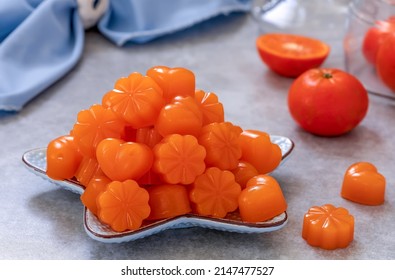 Homemade gummy candy made from citrus juice and agar agar. Heart and flower shaped orange jelly sweets served on a plate with fresh clementines on background. Horizontal, selective focus. - Shutterstock ID 2147477527