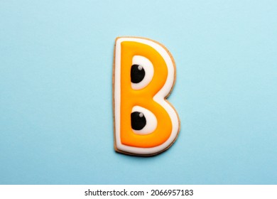 Homemade Halloween cookies in the shape of the letter B on a blue background.
