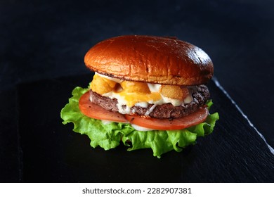 Homemade hamburger or burger with fresh vegetables. Burger with tomatoes on a black background.A quick snack. The concept of fast food. - Powered by Shutterstock