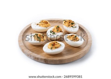 Homemade hard Boiled Deviled Eggs garnished with herbs isolated on white background.
