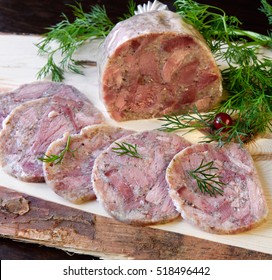 Homemade headcheese with dill and cranberries on a wooden board