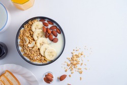 Homemade Healthy Breakfas,Bowl With Greek Yogurt, Banana Granola And Almonson,milks And Orange Juice And Bread On White Background.top View.
