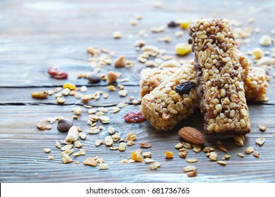 Homemade healthy cereal bars with granola, nuts and dried fruits on wooden background.