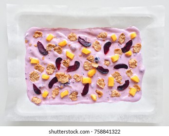 Homemade Healthy Frozen Cereal Blueberry Yogurt Bark With Mango And Cherry On A White Background, Tray Top View Close Up