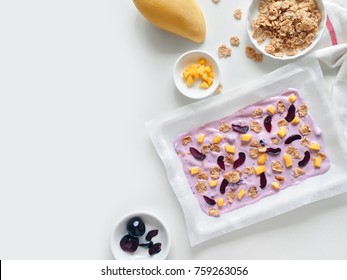 Homemade Healthy Frozen Cereal Blueberry Yogurt Bark With Mango And Cherry On A White Background, Top View Copy Space