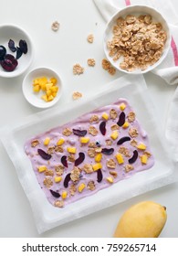 Homemade Healthy Frozen Cereal Blueberry Yogurt Bark With Mango And Cherry On A White Background, Top View