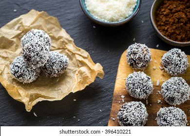 Homemade Healthy Paleo Raw Chocolate Truffles with Nuts, Dates and Coconut Flakes on Dark Background