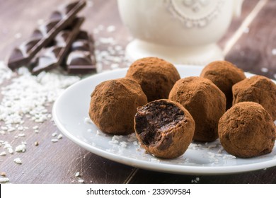 Homemade healthy vegan chocolate truffles with dates, coconut flakes and rolled oats served on white plate - Powered by Shutterstock