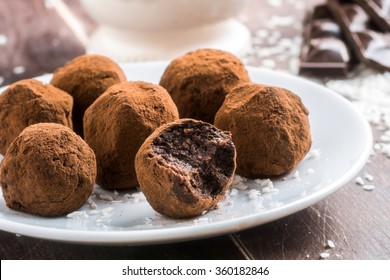 Homemade healthy vegan chocolate truffles with dates, coconut flakes and rolled oats served on white plate - Powered by Shutterstock