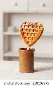 Homemade heart shaped waffle on a stick in a ceramic pot.