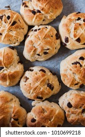 Homemade Hot Cross buns, spiced sweet on baking sheet with raisins and cross on top after baking fresh from the oven, traditionally eaten in the UK for easter celebrations on Good Friday after lent