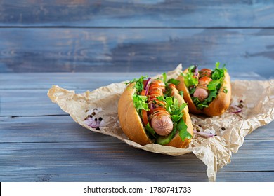 Homemade hot dog with sausage, salad, carrot, cucumber and tomato on wooden background