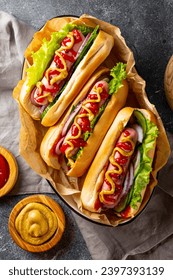 Homemade hot dogs with sausage, green salad, cucumber and red onion on the grey background top view vertical photo. High quality photo