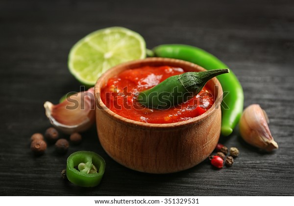 Homemade\
hot sauce and spices on dark wooden\
background