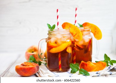 Homemade iced lemonade with ripe peaches and fresh mint. Fresh peach ice tea in a mason jar. Copy space background.