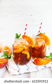 Homemade iced lemonade with ripe peaches and fresh mint. Fresh peach ice tea in a mason jar. Copy space background.