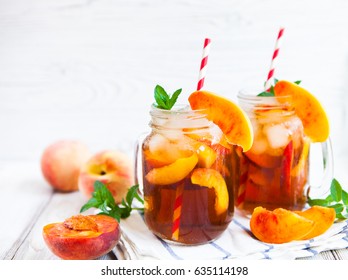Homemade iced lemonade with ripe peaches and fresh mint. Fresh peach ice tea in a mason jar. Copy space background.