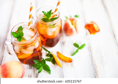 Homemade iced lemonade with ripe peaches and fresh mint. Fresh peach ice tea in a mason jar. Copy space background.
