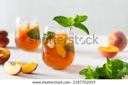 Homemade iced lemonade with ripe peaches and fresh mint. Fresh peach ice tea in glasses on white background with ingredients. Summer refreshing beverage recipe. Bar, cafe menu. Close up