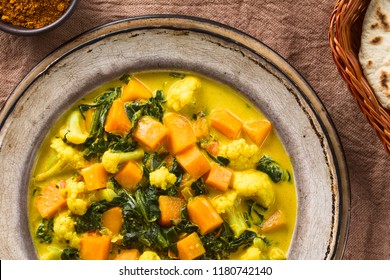 Homemade Indian Vegetarian Cauliflower Pumpkin And Spinach Curry In Soup Plate, Fresh Homemade Naan Bread On The Side, Photographed Overhead (Selective Focus, Focus On The Dish) 