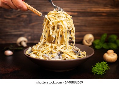 Homemade Italian fettuccine pasta with mushrooms and cream sauce (Fettuccine al Funghi Porcini). Traditional Italian cuisine. Served on a dark table with a rustic wooden background. Close-up - Powered by Shutterstock