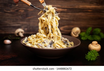 Homemade Italian fettuccine pasta with mushrooms and cream sauce (Fettuccine al Funghi Porcini). Traditional Italian cuisine. Served on a dark table with a rustic wooden background. Close-up - Powered by Shutterstock