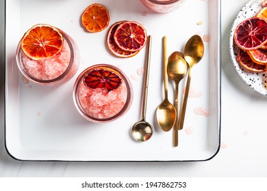 Homemade Italian Granita Dessert With Blood Orange, Elderflower, Rose Wine  In Serving Glasses On A White Metal Tray On A White Table. Flat Lay, Top View.