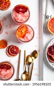 Homemade Italian Granita Dessert With Blood Orange, Elderflower, Rose Wine  In Serving Glasses On A White Metal Tray On A White Table. Flat Lay, Top View.