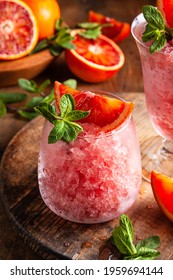 Homemade Italian Granita Dessert With Blood Orange, Elderflower, Rose Wine  In Serving Glasses On A Wooden Tray On A Wooden Table.