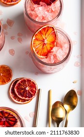 Homemade Italian Granita Dessert With Blood Orange, Elderflower, Rose Wine  In Serving Glasses On A White Metal Tray On A White Table.