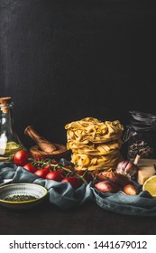 Homemade Italian Pasta With Cooking Ingredients On Dark Rustic Kitchen Table At Wall Background. Copy Space. Italian Cuisine. Still Life