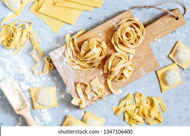 Homemade italian pasta, ravioli, fettuccine, tagliatelle on a wooden board and on a blue background. The cooking process, raw pasta. Tasty raw ravioli with ricotta and spinach,with flour on background - Powered by Shutterstock