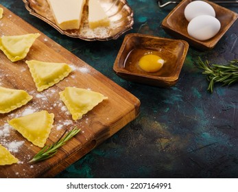 Homemade Italian Ravioli On A Wooden Cutting Board. Raw Products. Kitchen Utensils And Ingredients On A Dark Marble Background. Large Group Of Objects. There Are No People In The Photo.